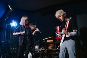 Zwei Musiker spielen Geige und E-Gitarre in einem kleinen Club