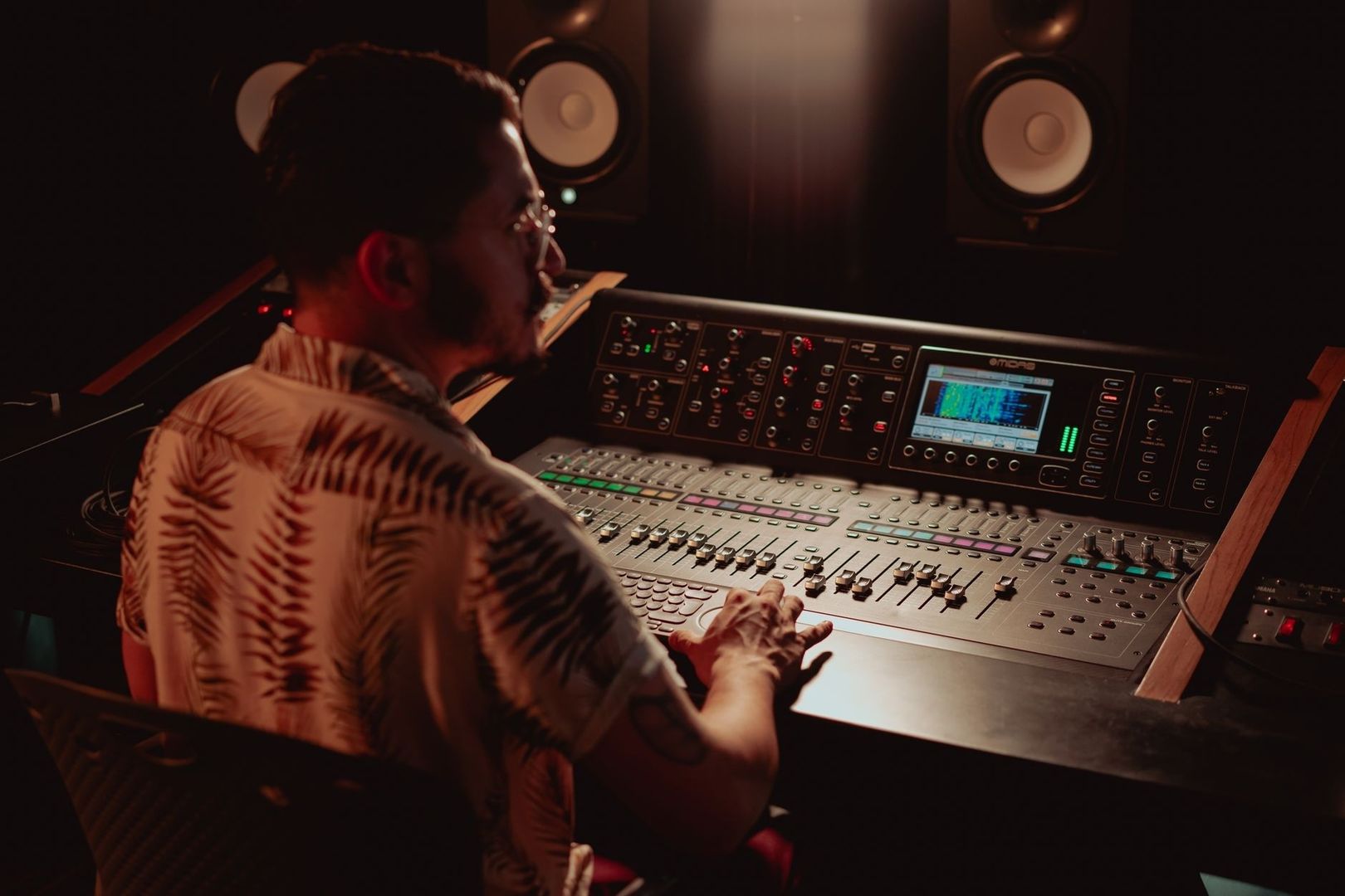 Tontechniker bedient ein digitales Mischpult im abgedunkelten Studio